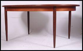 A 1970's G-Plan teak wood extending dining table raised on squared supports with oval table top.