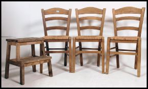 3 Rattan weave country dining chairs with railed back rests together with a vintage wooden stool.