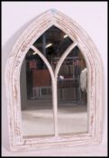 A 20th century contemporary painted shabby chic painted wall mirror of eclesiastical arched form