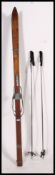 A pair of vintage wooden laminated cross country Norwegian skis and a pair of leather and alloy ski