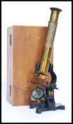 A small brass, likely Victorian microscope, within the original wooden case.