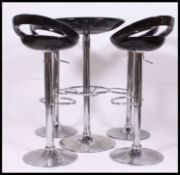A contemporary set of four rise and fall hydraulic pump action chairs along with a matching table