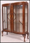 A 1930's walnut Queen Anne revival china display cabinet being raised on cabriole legs with glass