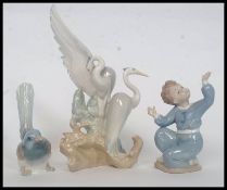A Lladro figurine of a finch together with a Lladro small boy and a Nao figurine of storks.