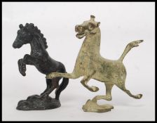 Two hollow cast metal horses, both in a prancing pose set on a naturalistic plinth.