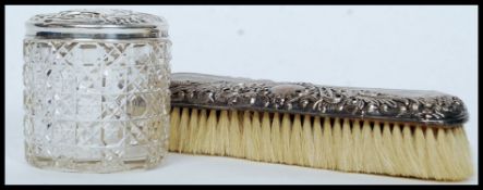 A silver hallmarked lidded cut glass dressing table pot along with a silver hallmarked brush,