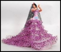 A vintage retro Spanish dancer doll, with large flowing purple dress, standing.
