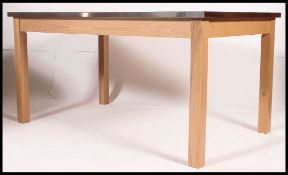 A large contemporary early 21st century oak dining table raised on square legs having a stainless