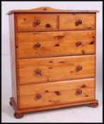 A contemporary two over three pine chest of drawers, being raised on bun feet.