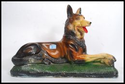 A large mid century plaster figurine of an Alsatian dog in seated position raised on a naturalistic