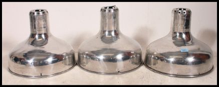 A set of 3 polished steel 20th century Industrial pendant shades.