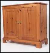 An contemporary pine sideboard / cupboard being raised on bracket feet having two long doors to the