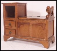 A 20th century golden oak hal settle telephone table having a lift up seat panel for storage,