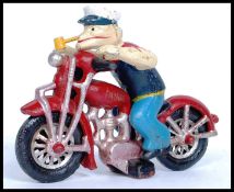 An unusual cast iron motorcycle and popeye figurine being hand painted.