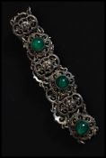 A ladies silver fret worked and green glass stone inset bracelet.