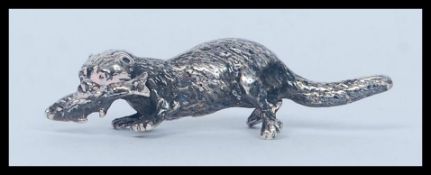 A SILVER MODEL OF A OTTER, a small miniature model of an otter with a fish in it's mouth,