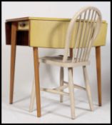 A 1950's retro yellow formica kitchen - dining  table raised on tapered supports with drop leaves