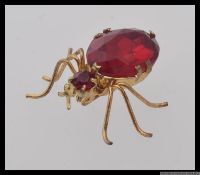 A vintage yellow metal bug brooch with large faceted red paste gem body. Measures 2.5cms x 4cms.