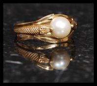 A 18ct gold and pearl ring having a snake adorned split shank,