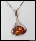 A silver Art Nouveau style amber pendant necklace chain in the manner of Archie Knox.