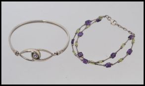 A silver braclet with twin lnked peacocks eye clasp with central amethyst stone together with a