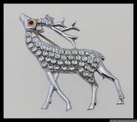 A 1950s white metal brooch of a stag figure with red rhinestone eye.