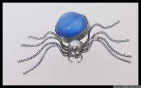A large white metal spider brooch with a blue cabochon body. Measures 3cms x 5cms. Weight 7.