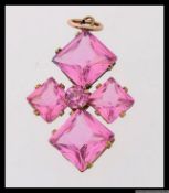 A 19th century yellow metal pendant set with dusky pink stones in the shape of a stylized cross.