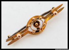 A 9ct twin bar brooch with central floral motif and applied finials. Marked 9ct. Weight 1.