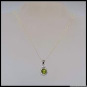 A 925 silver drop pendant necklace with inset green gemstone surrounded by round cut CZ.