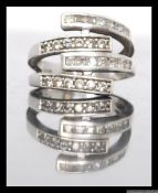 A silver ladies 925 marked overlapping band dress ring with round cut and baguette cut channel set