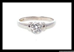 An 18ct white gold diamond single stone solitaire ring with rub over setting,