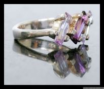A ladies silver 925 dress ring inset with two tone baguette cut amethyst stones. Size O.5.