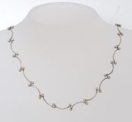 A pretty silver ladies shaped necklace with bow spacers and ball finials.
