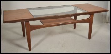 A retro 1970's G-Plan teak wood coffee table raised on tapered legs with magazine rack under