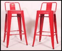 2 Industrial red metal tolix bar stools. Pressed metal construction with pierced seats.