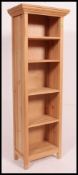 A tall contemporary stripped light pine upright bookcase cabinet with flared top and fixed shelves.