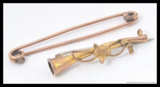 A 9ct gold hunting brooch depicting  a fox and riding crop over a hunting horn along with a gold