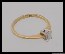 An 18ct 750 gold ring set with a single emerald cut diamond of .25pts. Hallmarked for Birmingham.