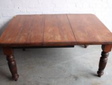 A Victorian mahogany dining table being raised on turned legs with extending centre