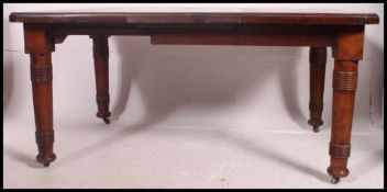 A large 19th century Victorian dining table raised on turned legs on brass castors