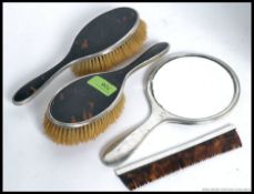 A decorative hallmarked silver and tortoiseshell part vanity set - to include mirror,