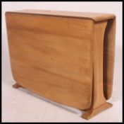 An Ercol beech and elm wood light drop leaf sutherland occasional - coffee table being raised on