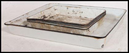 A collection of five mid 20th century vintage industrial oversized enamel trays,