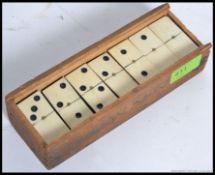 An early 20th century bone fronted ebonised domino set in the wooden case ( lacking cover )