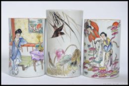 A pair of Chinese famille rose ceramic brush pots having decorative family scenes / scholars.
