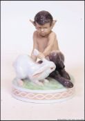 A Royal Copenhagen porcelain figure group of a young faun playing with a white rabbit.