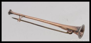 An early 20th century brooch in the form of a hunting horn / bugle. 9ct gold with silver ends.