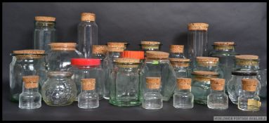 A collection of kitchen glass jars of various sizes and shapes, some with cork stoppers.