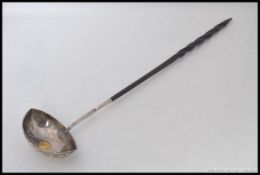 An antique white metal (silver, but unmarked) and horn handled ladel. The base set with a coin.